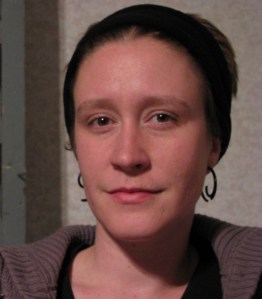 Laurel, wearing black headband and hoop earrings
