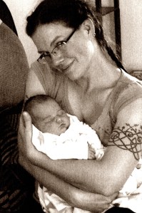 Lyssa smiling with glasses holding baby.