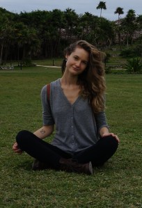 Photo of Carlyn, sitting cross-legged in the grass