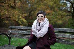 Person with dark hair sitting on a bench with a light pink scarf